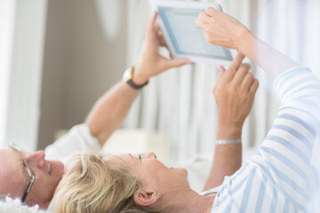 Obraz na płótnie Canvas Older couple using digital tablet on bed