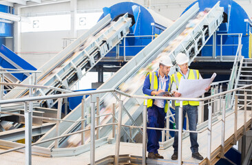 Workers reading blueprints in recycling center