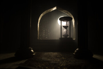 Silhouette of hourglass inside room. Abstract surreal idea with empty space. Selective focus