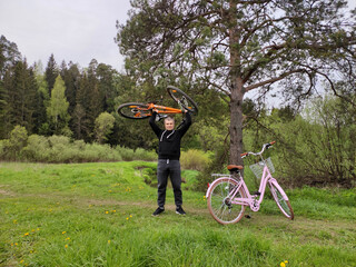 A young man is resting in the forest on a forest glade. Man lifted his sport bike over his head....