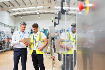 Fototapeta Supervisor and worker using digital tablet in factory obraz