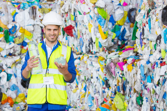 Worker Holding Compacted Plastic Bottle In Recycling Center