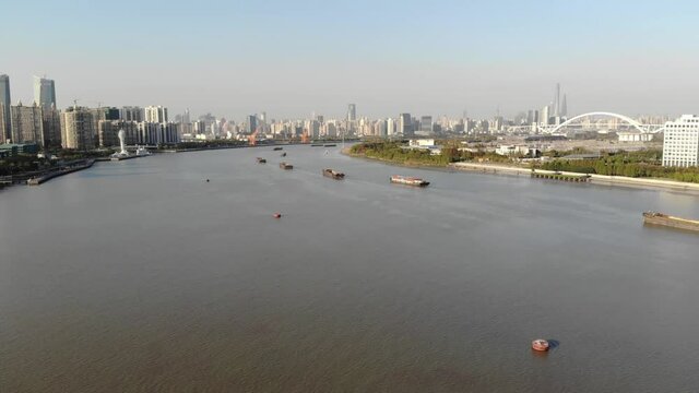 Barges and ships on Huangpu river in downtown Shanghai. Chinese inland shipping lane in major metropolis trading goods. Boats ferrying products  into major metropolitan center.