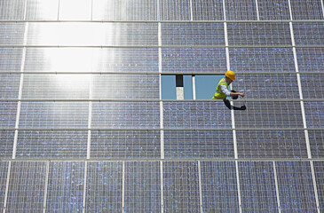 Worker examining solar panel in rural landscape