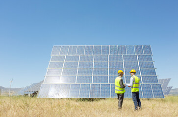Workers examining solar panel in rural landscape
