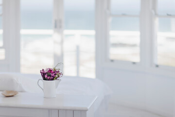 Vase of flowers on desk in bedroom overlooking ocean