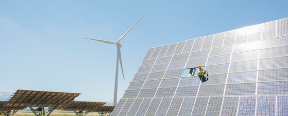 Worker examining solar panel in rural landscape