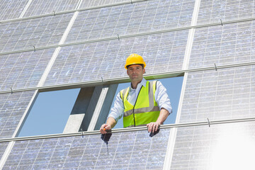 Worker examining solar panel in rural landscape