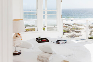 Breakfast tray and magazine on bed overlooking ocean