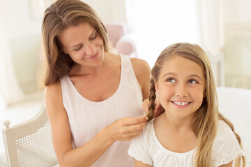 Obraz na płótnie Canvas Mother braiding daughter's hair