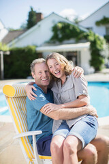 Fototapeta premium Couple sitting in lounge chair at poolside