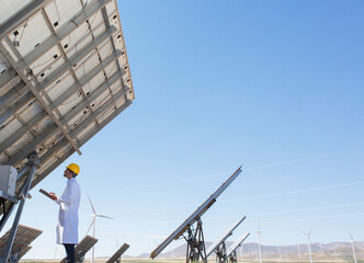 Scientist examining solar panel in rural landscape
