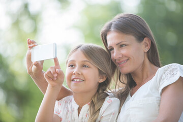 Mother and daughter using cell phone outdoors