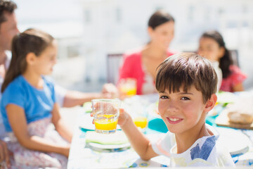 Obraz na płótnie Canvas Boy drinking juice at table on sunny patio