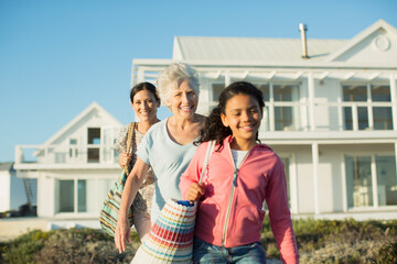 Multi-generation women walking on beach path outside house