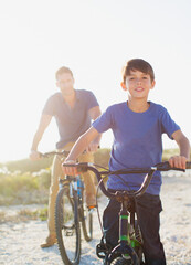 Naklejka premium Father and son riding bicycles on sunny beach