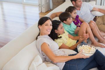 Obraz na płótnie Canvas Family watching movie on sofa in living room
