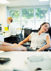 Fototapeta premium Businesswoman napping at desk in office