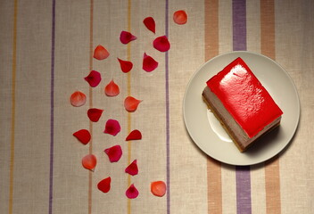 Deser ciasto ptasie mleczko trzy kolorowe warstwy z czerwoną galaretką na górze, na białym...