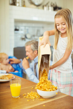 Girl Pouring Bowl Cereal On Breakfast Table