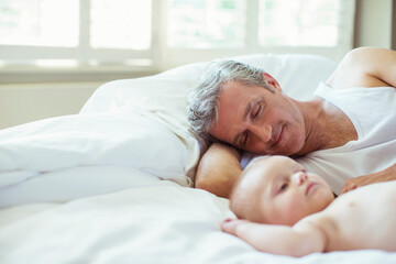 Father and baby laying on bed