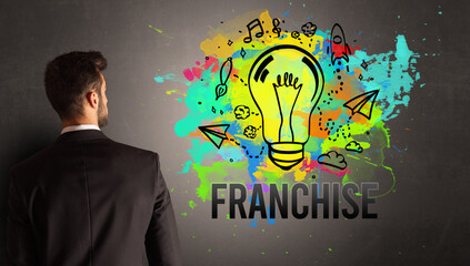 businessman drawing colorful light bulb with FRANCHISE inscription on textured concrete wall, new business idea concept