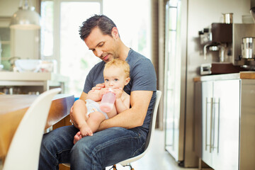 Father feeding baby in kitchen