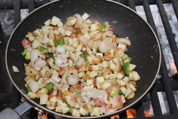 potato ,egg and ham breakfast cooking over campfire