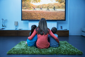 Mother and children watching television in living room