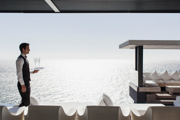 Waiter serving champagne at cabana overlooking ocean © Martin Barraud/KOTO