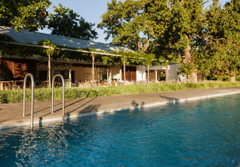 Swimming pool outside luxury house surrounded by trees