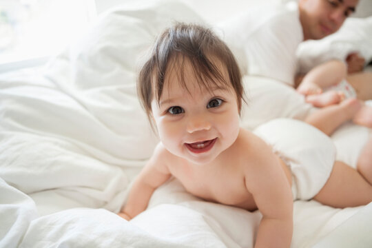 Baby girl crawling in bed sheets