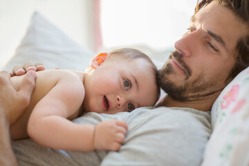 Father laying with baby boy on bed