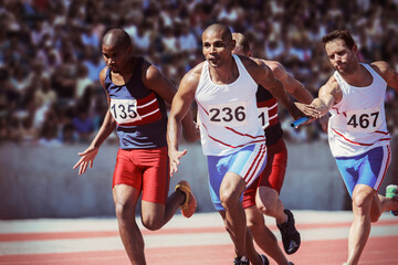 Relay runners exchanging batons on track