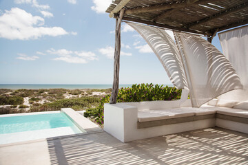 Curtains blowing in wind on luxury poolside patio overlooking ocean