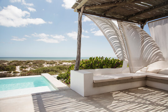 Curtains Blowing In Wind On Luxury Poolside Patio Overlooking Ocean