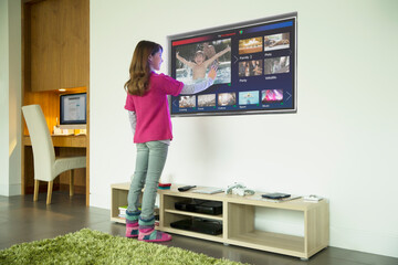 Fototapeta na wymiar Girl using touch screen television in living room