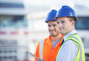 Businessman and worker using digital tablet near trucks