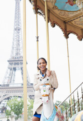 Woman riding carousel near Eiffel Tower, Paris, France
