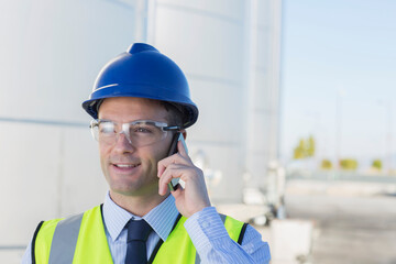 Close up of worker talking on cell phone in front of silage storage tower