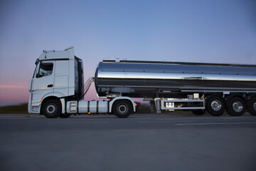 Obraz premium Stainless steel milk tanker on the road at night