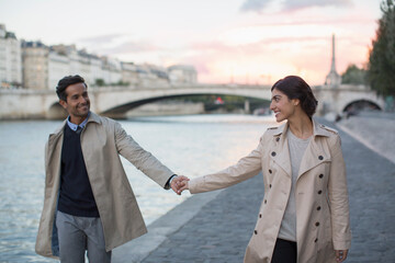 Couple holding hands along Seine River, Paris, France