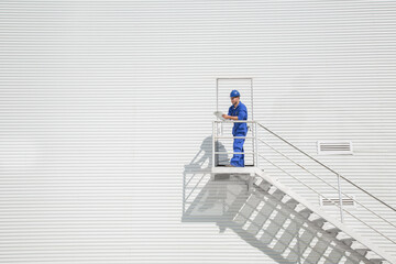 Worker with clipboard on stairs along building