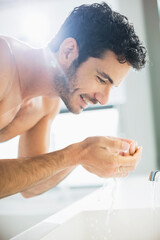 Obraz na płótnie Canvas Close up of man washing face at sink