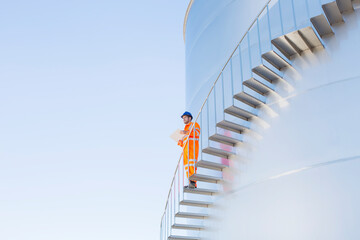 Worker with paperwork on stairs along silage storage tower