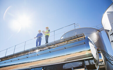 Workers on platform above stainless steel milk tanker