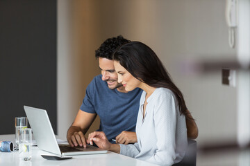 Obraz na płótnie Canvas Couple using laptop at table
