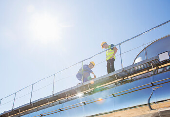 Workers on platform above stainless steel milk tanker