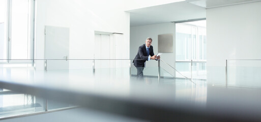 Businessman standing at railing in office
