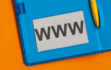 WWW text is written in black letters on a business card lying in a blue diary. Text made in...